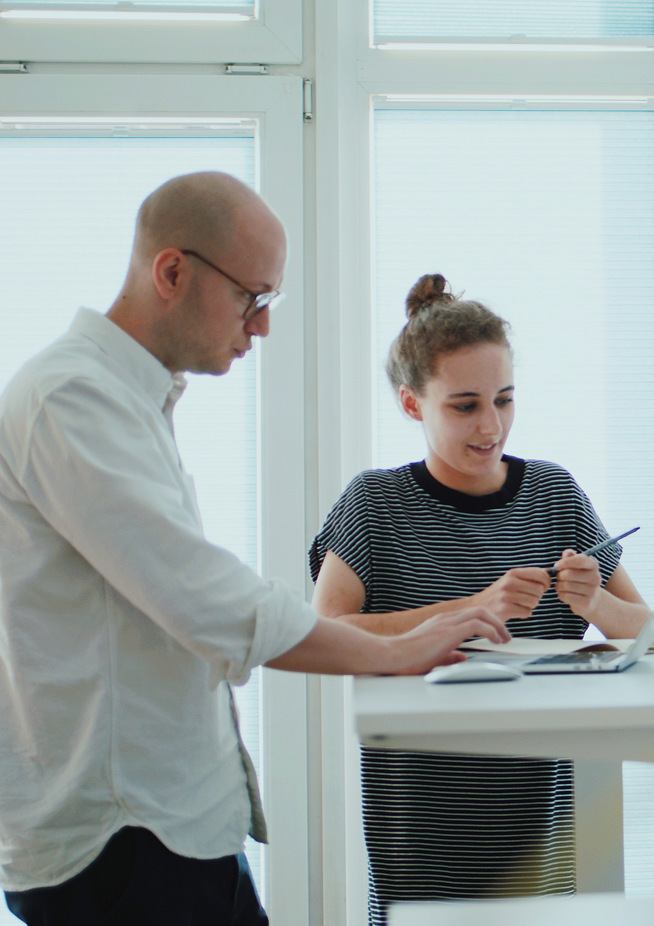 Zwei Mitarbeitende der Designagentur Radikant unterhalten sich an einem Stehtisch mit Laptop