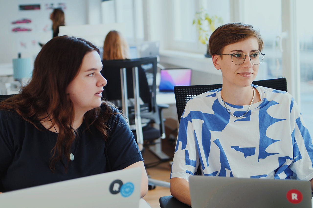 Zwei Mitarbeiterinnen der Designagentur Radikant in einem Gespräch bei der Arbeit mit Laptops